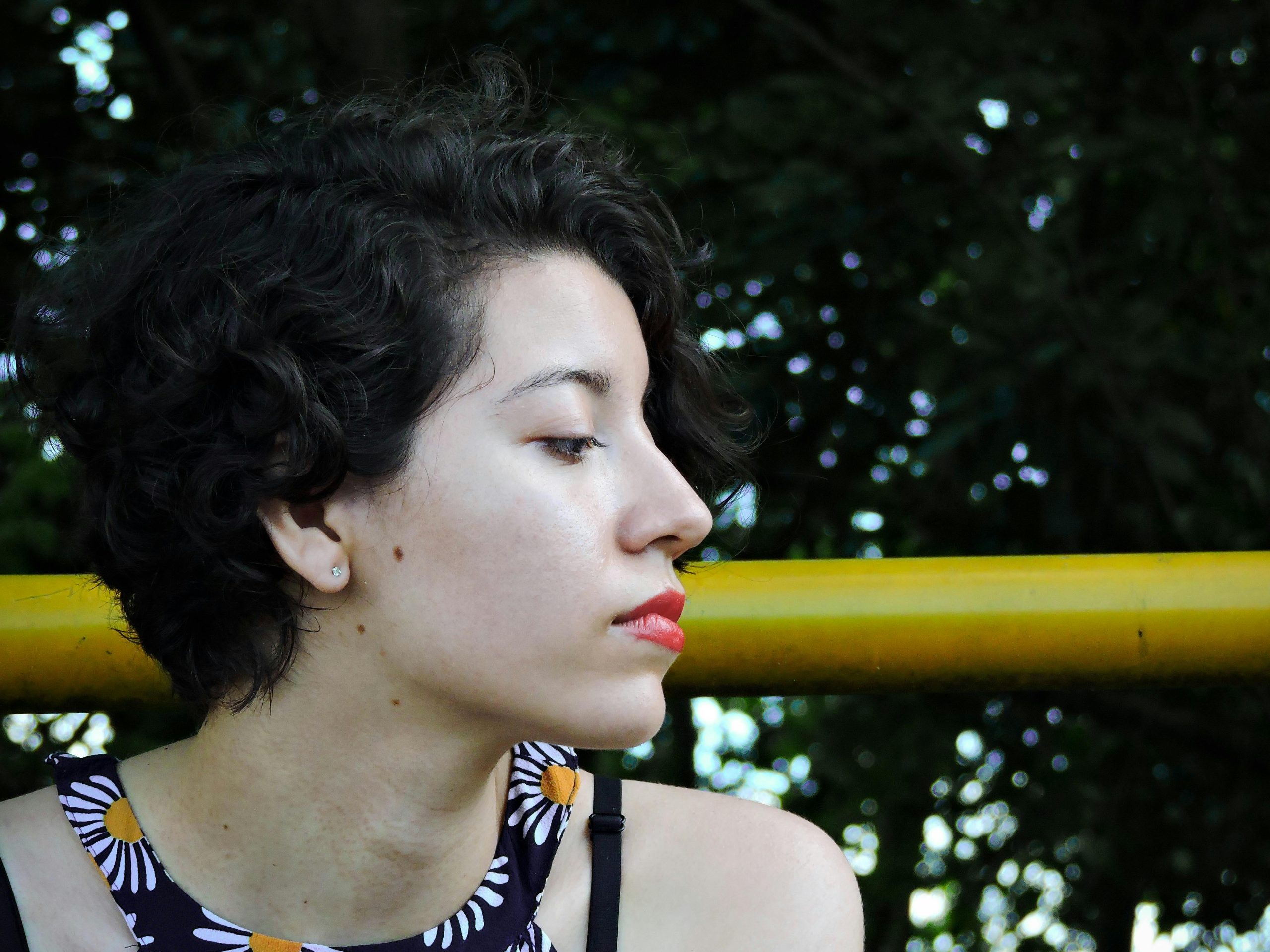 Profile portrait of a young woman with short curly hair, enjoying leisure outdoors.